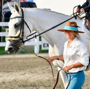 A horse handler beside a gray horse at an equestrian event
